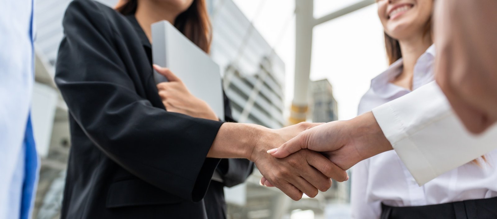 Close up of businesswoman and man making handshake outdoor in the city.