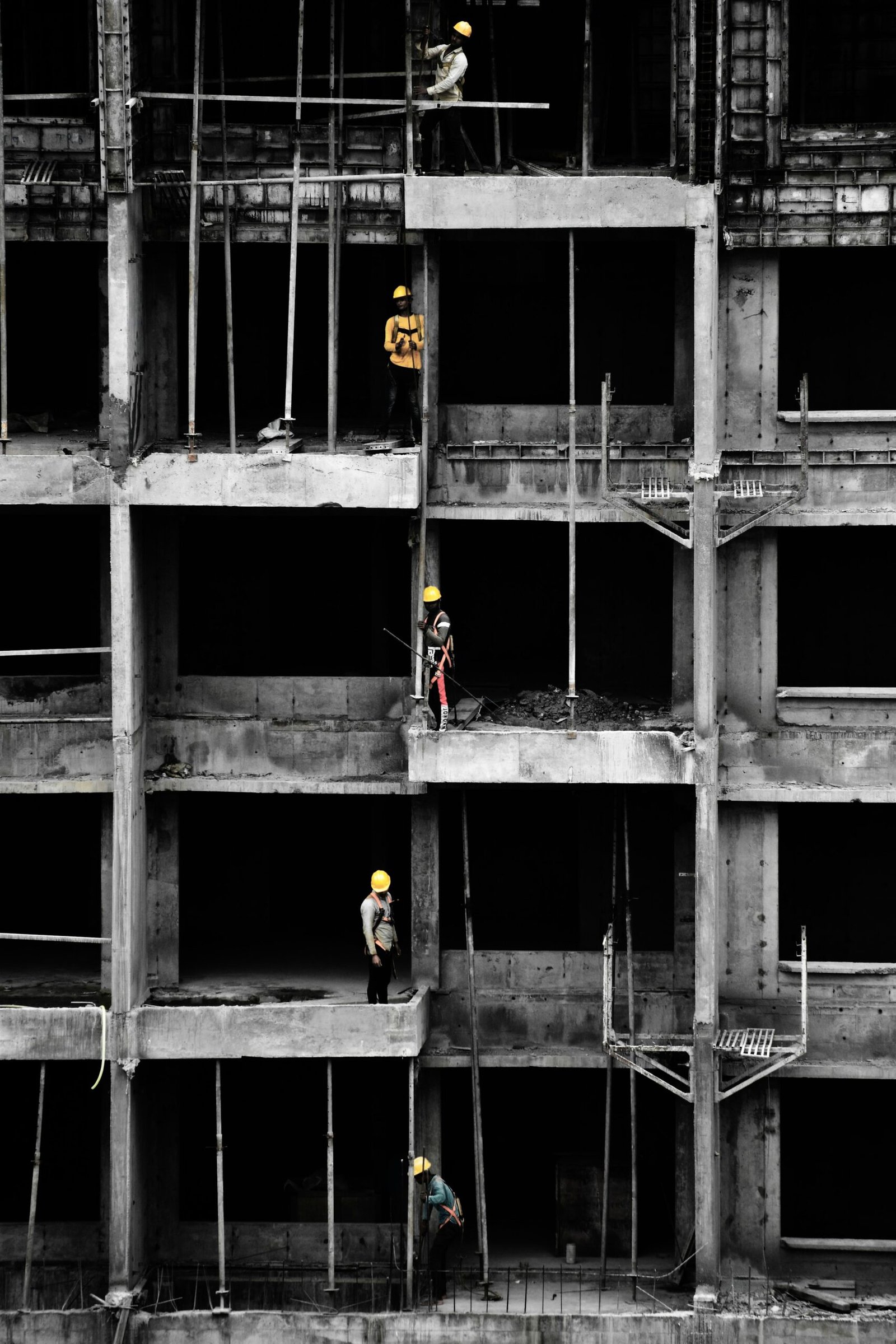 Ossature en béton d’un immeuble en chantier, deux compagnons casqués au travail