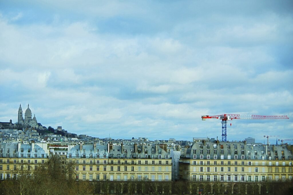 Rangées d’immeubles d’habitation parisiens, une grue de chantier au-dessus des toits et le Sacré-Cœur au loin